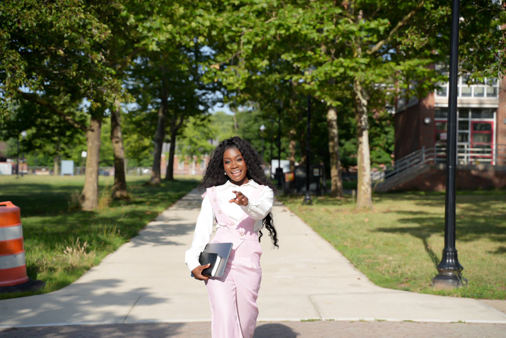 Ink Duncan laughing and pointing as she walks across a campus path